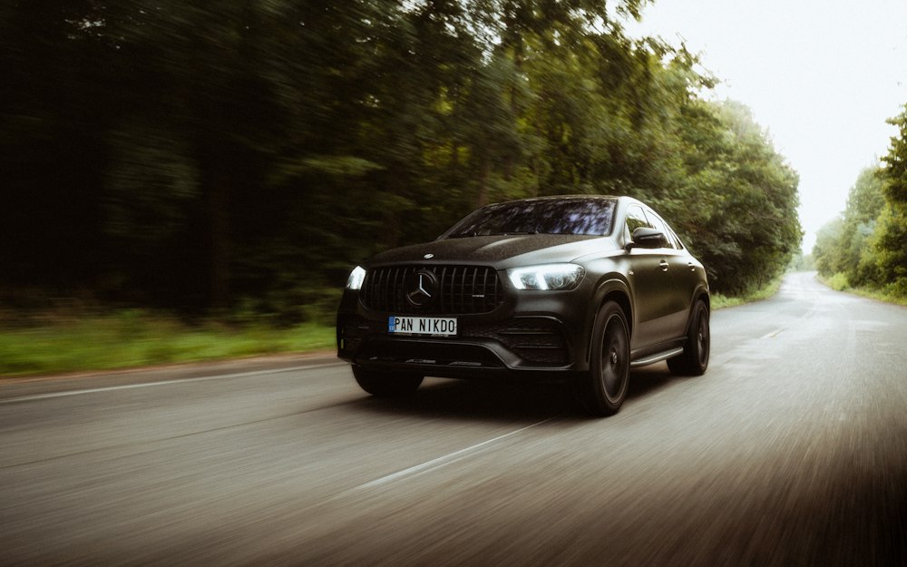 Black Mercedes SUV driving on a country road